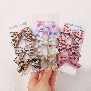 Detailed set of 9 fabric bow hair clips with floral and plaid patterns on white cards