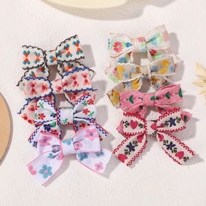 Detailed view of eight assorted bow hair clips with floral and polka dot patterns