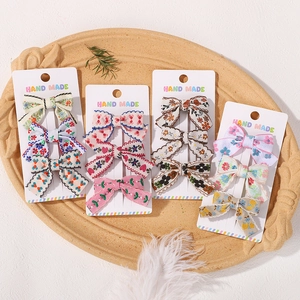 Detailed macro view of handmade fabric bow hair clips with diverse embroidery patterns