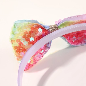 Close-up of rainbow sequin bow headband with golden glitter center and non-slip teeth detail