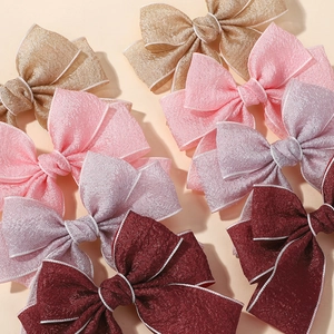 Detail of fabric bow hair clips with white stitched edges in multiple pastel colors