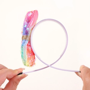 Detail showing the flexible lilac headband with non-slip teeth and colorful sequin bow