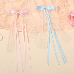 Detalle de pinzas para el cabello con lazos de gasa rosa y azul y cintas largas de encaje