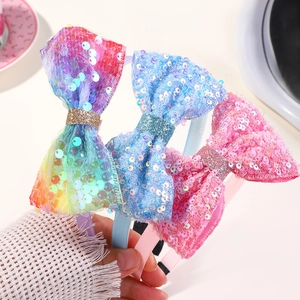 Close-up of children's sequin bow headbands in rainbow gradient, blue, and pink colors
