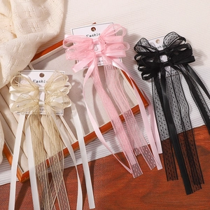 Barrettes à nœud en dentelle avec longs pompons en champagne, rose et noir exposées