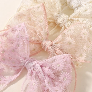 Gros plan sur la broderie de marguerites délicates sur des nœuds de cheveux en dentelle
