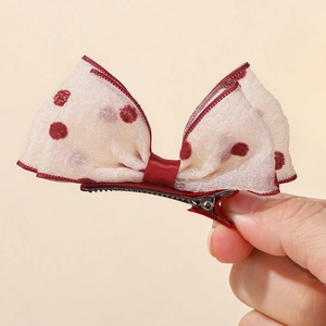 Detail of red polka dot mesh bow hair clip with metal alligator base and mesh texture