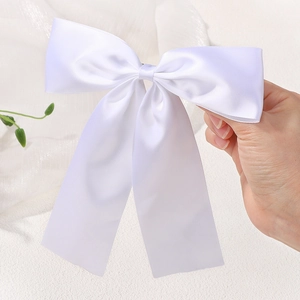 Close-up of white satin bow hair clip with long ribbons held by hand for detail