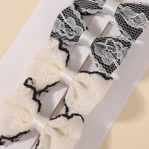 Detail of lace bow hair clips with black and white satin accents on a display card