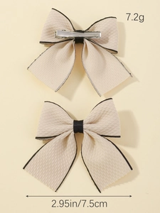 Detail view of cream fabric bow clips with black trim showing 7.5cm size and 7.2g weight
