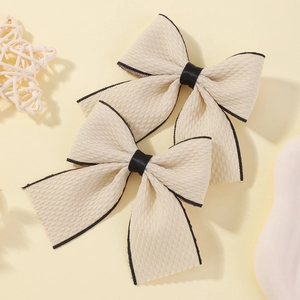 Pair of cream fabric bow hair clips with black edge finish and satin center tie