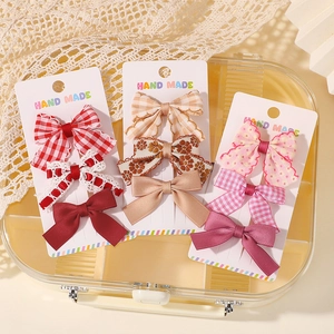 Détail de neuf barrettes brodées main aux motifs floraux et vichy dans une boîte cadeau