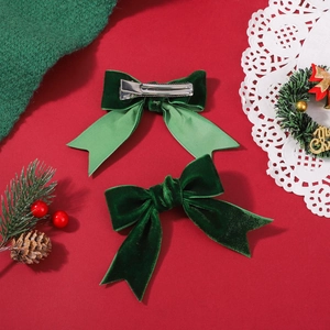 Detail view of dark green velvet bow hair clips with silver metal duckbill clips