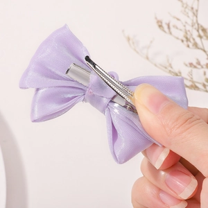 Détail d'une pince à cheveux à nœud en satin violet clair avec fermoir en métal argenté