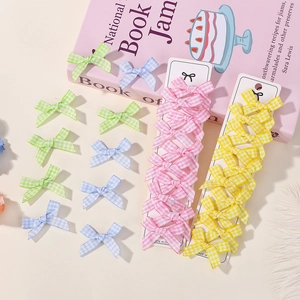 Detail of plaid fabric bow hair clips in pastel colors displayed on a white cardboard