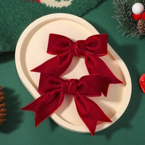 Pair of red velvet bow hair clips for girls with festive holiday decoration on tray