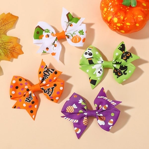 Close-up of four Halloween bow hair clips with pumpkin, ghost and candy patterns