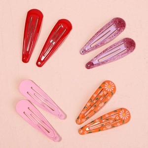Flat lay detail of 8-piece floral and glitter metal BB hair clips on pink background