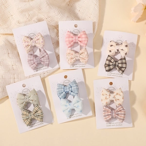 Détail de 12 barrettes à nœuds en tissu fleuri et à pois sur des cartes blanches