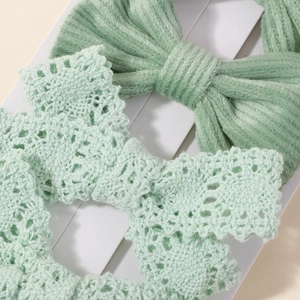Detailed macro view of light green hand-crocheted baby headband with bow and openwork pattern