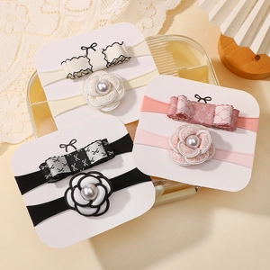 Detailed view of elastic baby headbands with fabric camellia flowers and faux pearls