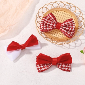 Detailed view of red and houndstooth bow hair clips set with ribbon and velvet textures