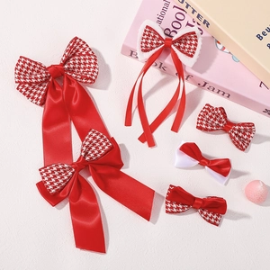 Close-up of red ribbon hair bows with houndstooth pattern and plush white trim details