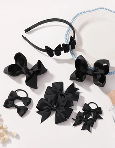 Detailed set of black ribbon bow headbands and hair clips for girls on a vintage tray