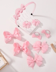 Detailed set of pink bow hair clips and a pearl headband on a white background