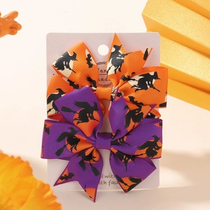 Macro detail of Halloween bow hair clips with witch prints on orange and purple grosgrain
