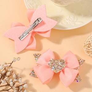 Détail d'un nœud rose avec cœur pailleté et pince croco en métal pour filles