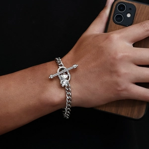Close-up of cuban link bracelet with sparkling bear charm and OT buckle on wrist