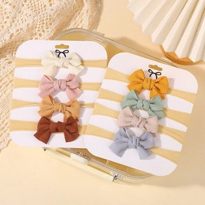 Eight-piece set of striped knit baby headbands with handmade bows in assorted soft colors