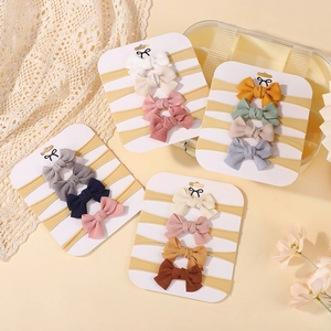 Detailed view of 16-piece set bow headbands on white cards with ribbed fabric textures