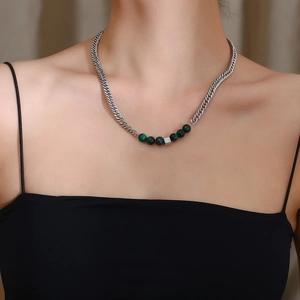 Détail de perles d'oeil de tigre vert et cube en cristal sur chaîne en acier argenté