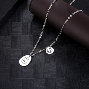 Collier en acier inoxydable argenté avec pendentifs emoji smiley sur fond noir texturé