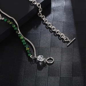 Macro detail of OT buckle necklace with jade-style green beads and crystal on black texture