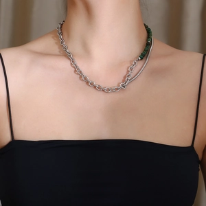 Detail view of asymmetric necklace featuring silver chain links and green jade beads