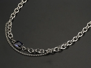 Detail of a double-layered titanium steel necklace with an emerald-cut blue sapphire pendant
