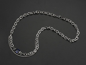 Macro shot of silver titanium chain necklace with blue sapphire zircon pendant detail