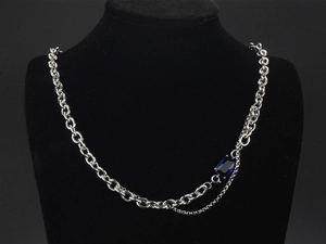 Detail of a double-layered titanium steel necklace with a blue sapphire gemstone pendant