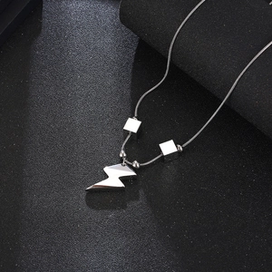 Macro shot of silver lightning bolt pendant with cube beads on a sleek snake chain