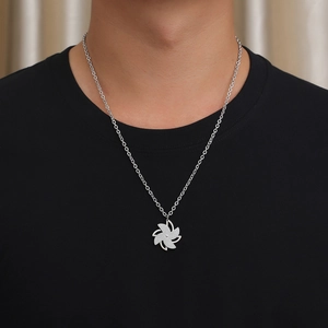 Detail of silver rotating windmill pendant with sparkling finish on a men's neck