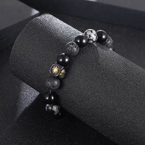 Detail shot of black onyx and snowflake obsidian beads with a gold star square charm