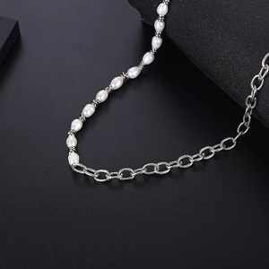 Collier en perles baroques et chaîne à maillons argentés sur fond noir texturé
