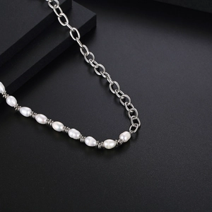 Collier moderne en perles baroques et maillons argentés sur un socle noir chic
