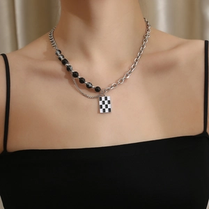 Detail of double-layer titanium steel necklace with checkerboard pendant and marble beads