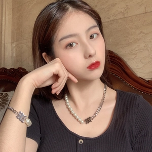 Gros plan d'un ensemble bracelet perles et chaîne en acier titane sur le poignet d'un mannequin