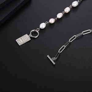Macro detail of irregular pearls and silver square pendant with OT buckle closure