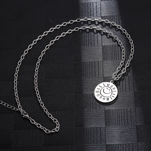 Detailed view of silver sun smile pendant on stainless steel chain over black mesh background
